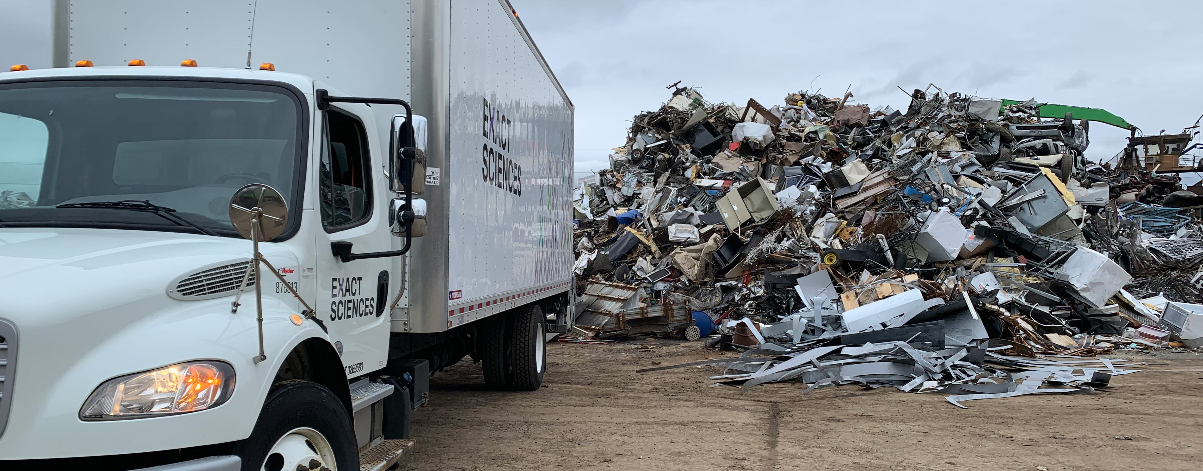 a white truck with the Exact Sciences logo next to a pile of scrap metal
