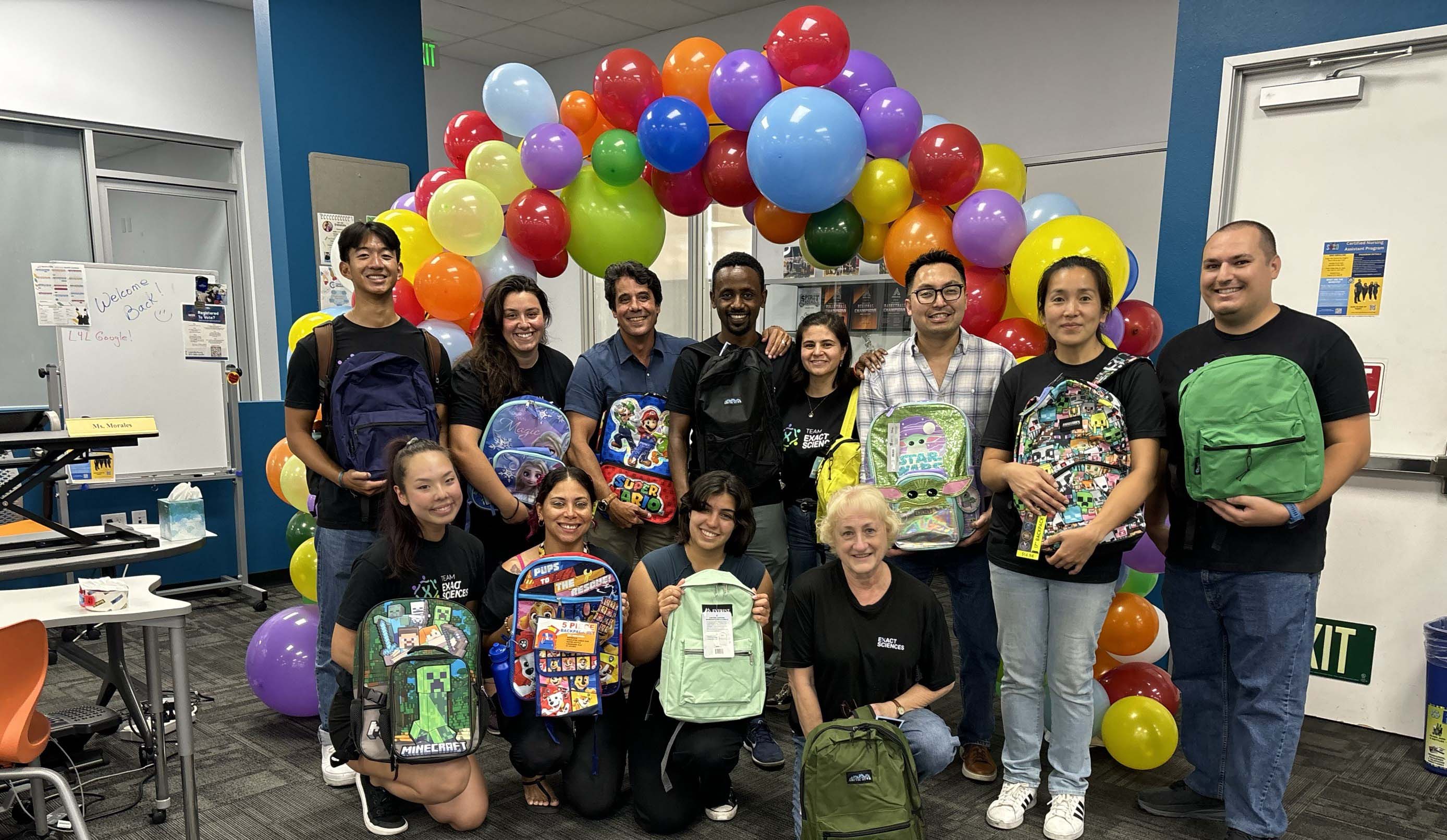 Volunteers posing with backpacks for kids