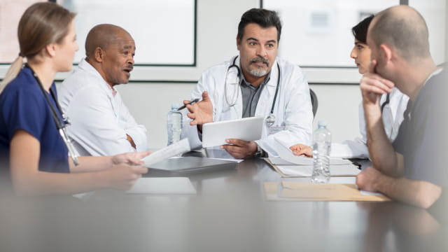 A group of health care staff sitting at a conference table having a discussion.