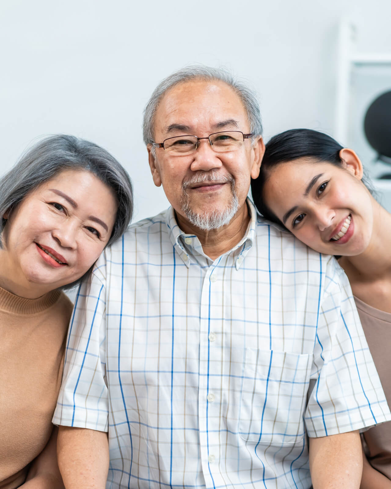An older man and woman with a younger woman, all smiling at the camera.