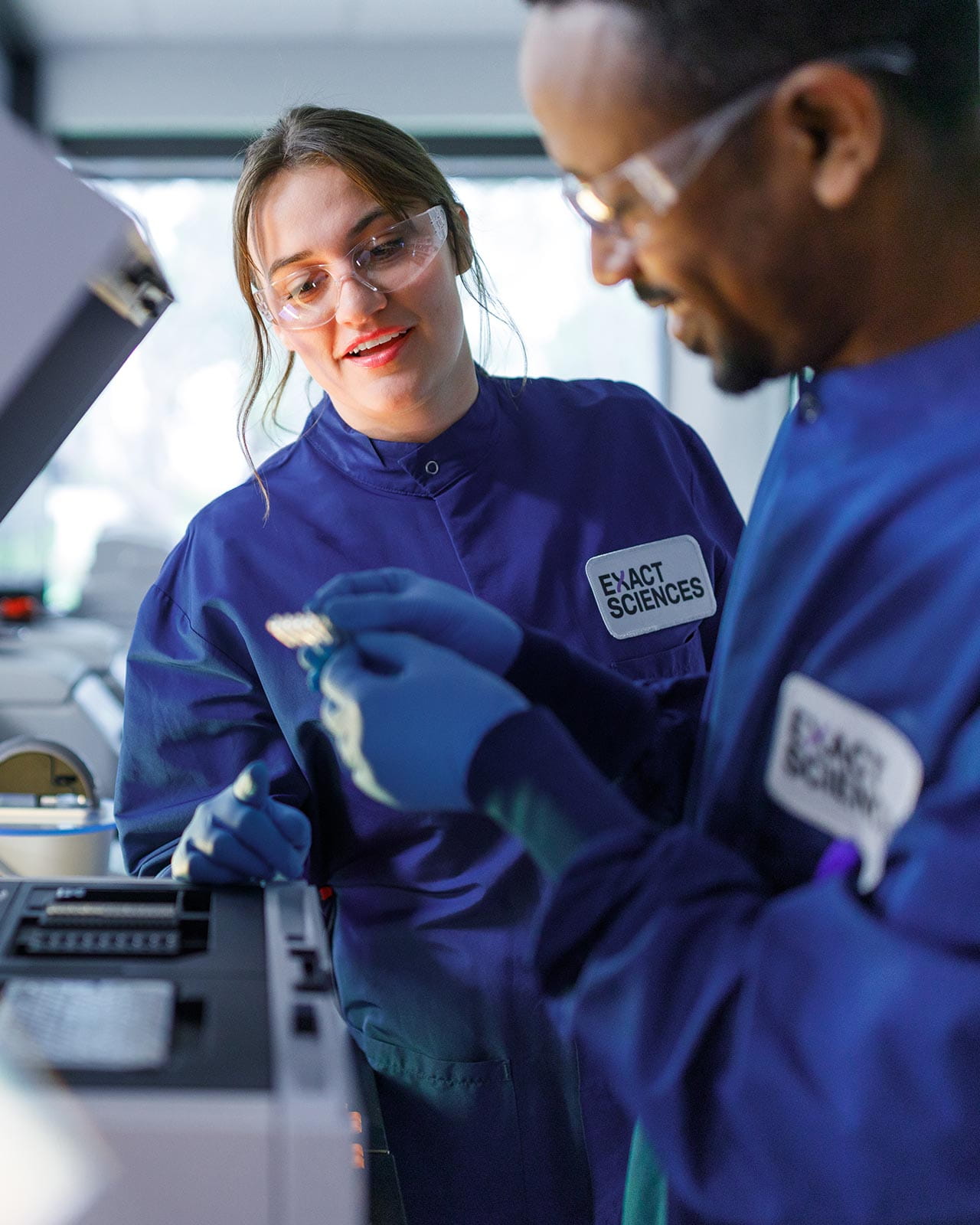 Two Exact Sciences lab technicians examining a lab specimen.