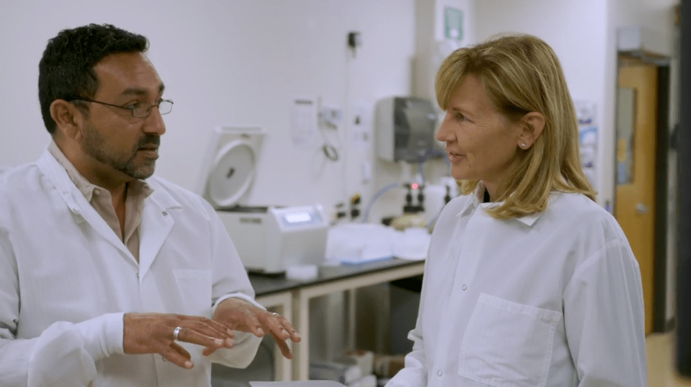 Two people in lab coats talking in a laboratory