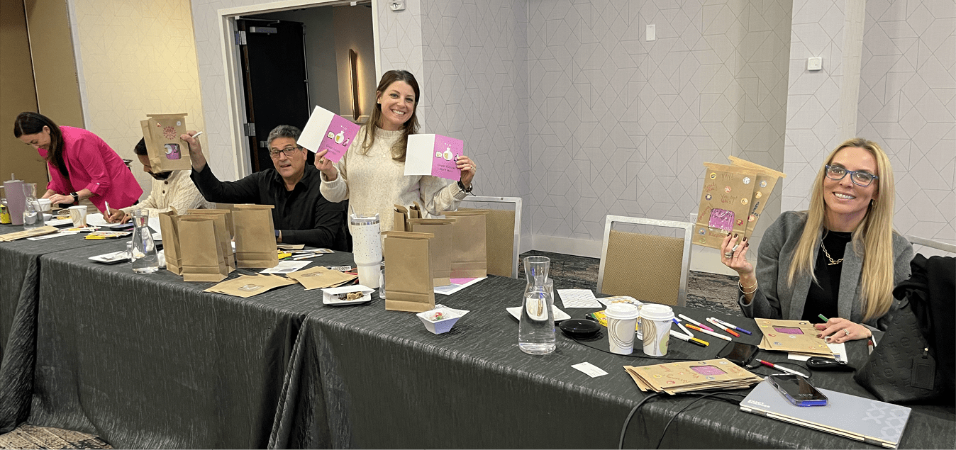Colleagues smiling and holding handmade cards during a team card-making activity.