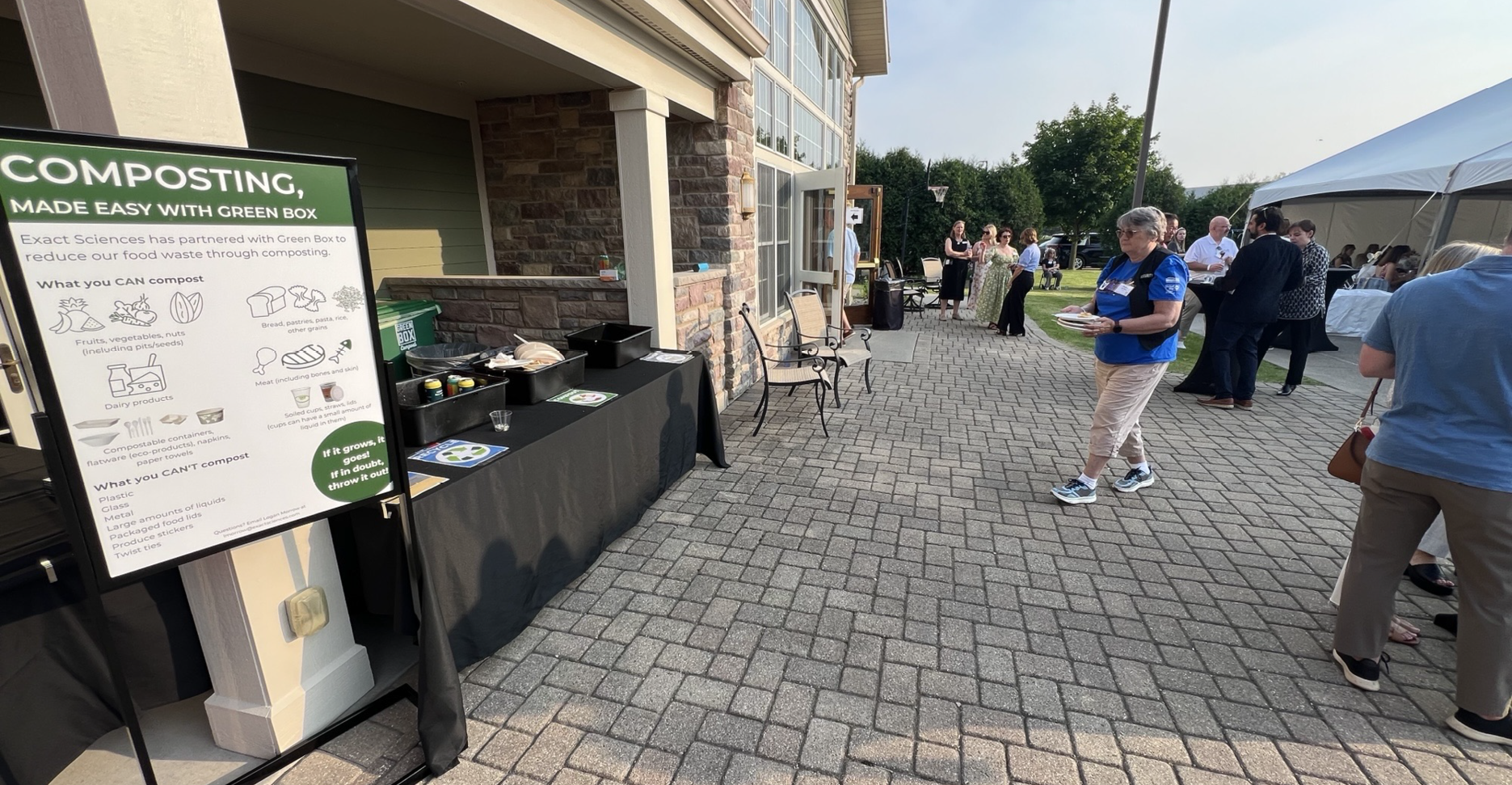 Composting station and educational sign at an outdoor non-profit event.